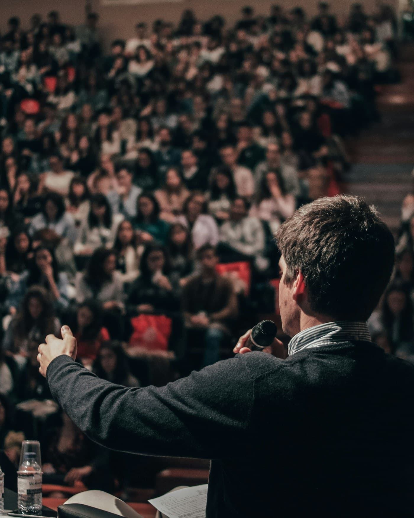 An instructor speaking to a large hall of learners.